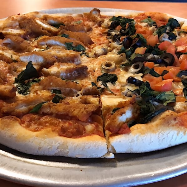 Aljon's Grill Pizzeria's half chicken cutlet and half vegetable pizza with olives and tomatoes.
